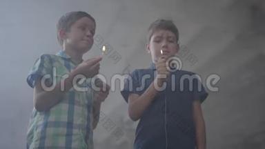 两个男孩在一个烟雾弥漫的废弃房间里。 一个男孩拿着燃烧的火柴，第二个男孩拿着燃烧的打火机